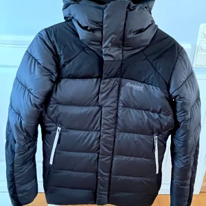 Fin vinter/skidjacka dam från Bergans - Women's Rabot 365 Down Jacket från Bergans är en syntet och dunfodrad jacka som passar utmärkt till friluftsliv/skidåkning vintertid.  Jackan är svart och grå, mycket varm och har en snygg boxig passform. Vind- och vattentät. Jackan är i nyskick. 