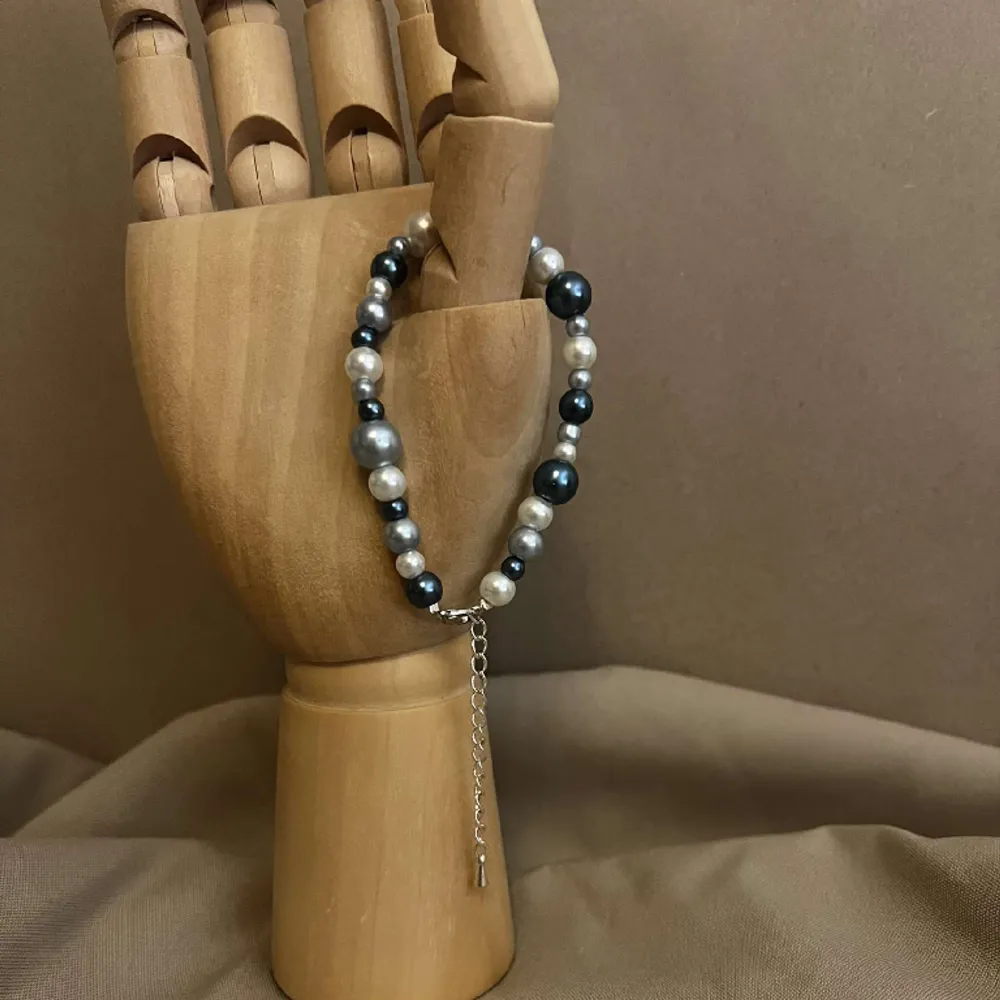 Armbandet Eleonore består av flera olika storlekar av pärlor i olika färger av blått med silver lås och kedja.  Namn: Elonore Längd: Hela 23 cm Pärlor 15,5 cm. Accessoarer.