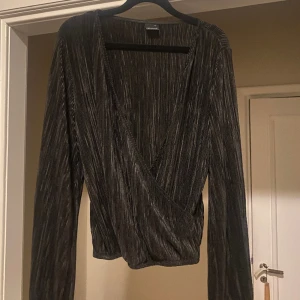 Svart tröja  - Svart tröja med veckad/ribbat? tyg. Djup v-ringning och funkar utmärkt att ha bak och fram för en öppen rygg