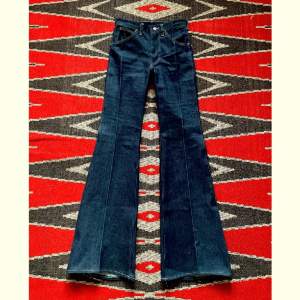 Jävligt fräsiga vintage deadstock jeans i utsvängd modell av Wrangler Blue Bell på 1970-talet.   Midja - 35cm Höfter - 40cm Gren - 26cm Längd - 118cm Innersöm - 86cm  100% bomull, kraftigt bruten krypert denim  Skriv för fler bilder och mer info!