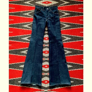 70-tal, Wrangler Blue Bell jeans - Jävligt fräsiga vintage deadstock jeans i utsvängd modell av Wrangler Blue Bell på 1970-talet.   Midja - 35cm Höfter - 40cm Gren - 26cm Längd - 118cm Innersöm - 86cm  100% bomull, kraftigt bruten krypert denim  Skriv för fler bilder och mer info!