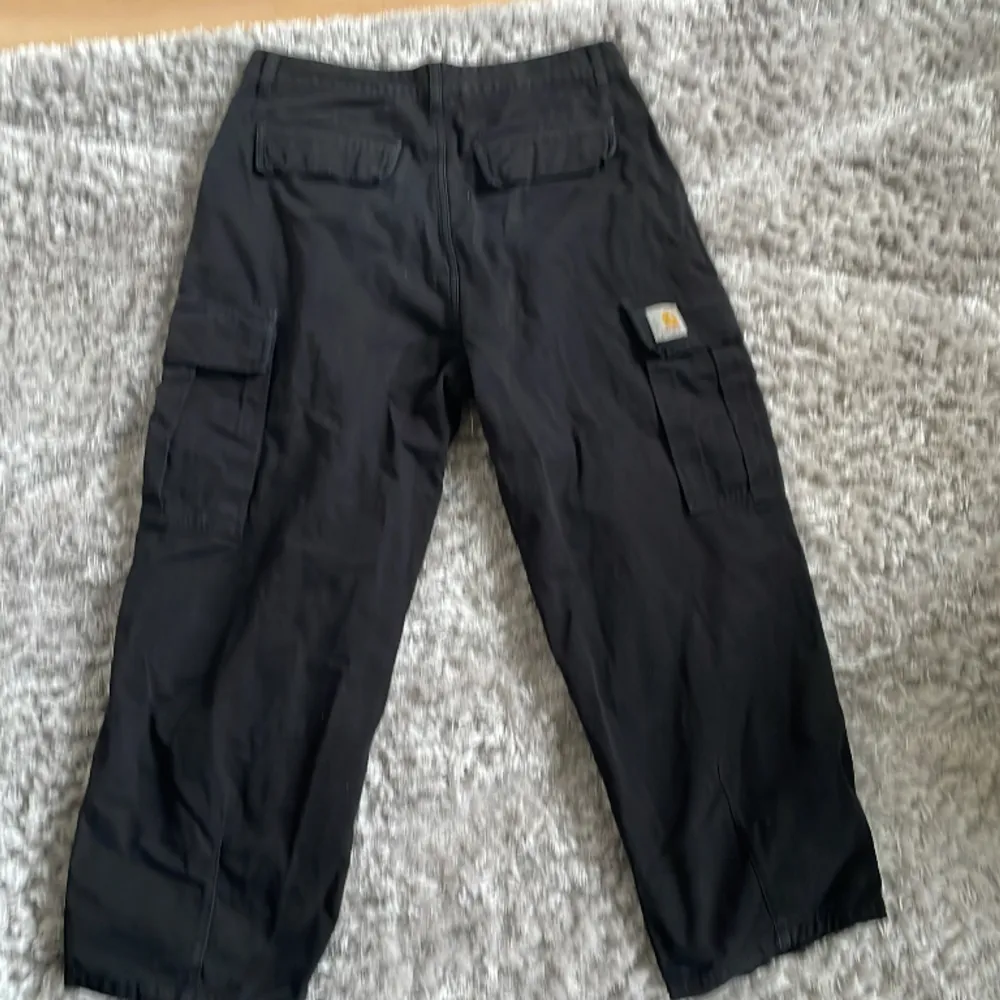 Svarta Carhartt cargos med en lös passform. 2 cargo fickor, 2 backfickor och 2 sid fickor. Ny pris ca 1400 kr  Har använts mycket! Inga skador eller tydliga fäckar. Jeans & Byxor.