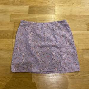 Lila blommig kjol med en liten slits och dragkedja, super bra kvalite och super skön. Knappast använd, skriv privat för fler bilder 