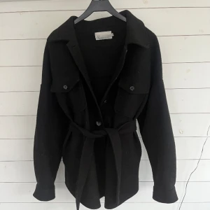 Kappa - Svart kortare kappa från Nelly. Storlek 34 men passar större storlek också. Inga defekter alls! Skriv gärna vid frågor🫶🏼 Frakt tillkommer