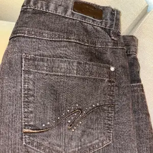 Grå/svarta jeans med fina broderade fickor med stenar. Modellen straight. Väldigt stretchiga, midjemått 76 cm. 