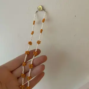 Ett vitt halsband med orangea blommor på💗