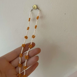 Orange och vitt halsband  - Ett vitt halsband med orangea blommor på💗