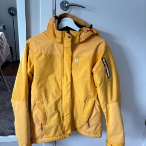 Gul/orange skidjacka - Säljer min gul/orangea skidjacka som är för liten för mig. Använd fåtal gånger, har en svart prick på ryggen men annars mycket bra skick. Skriv om ni vill veta mått eller annat😊💓pris kan diskuteras 🥰köpare står för frakten