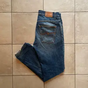 Nudie Jeans i modellen Grim Tim🕺| Skick: Fint skick med en riktigt snygg åldring/fade⭐️| Storlek: W32/L32 | Pris: 399✔️, Nypris: 1600kr❌| OBS! Hål på båda ben, som visas på bild två. Dessa kan lagas gratis på Nudie butik, jag kan lämna in efter köp🤝