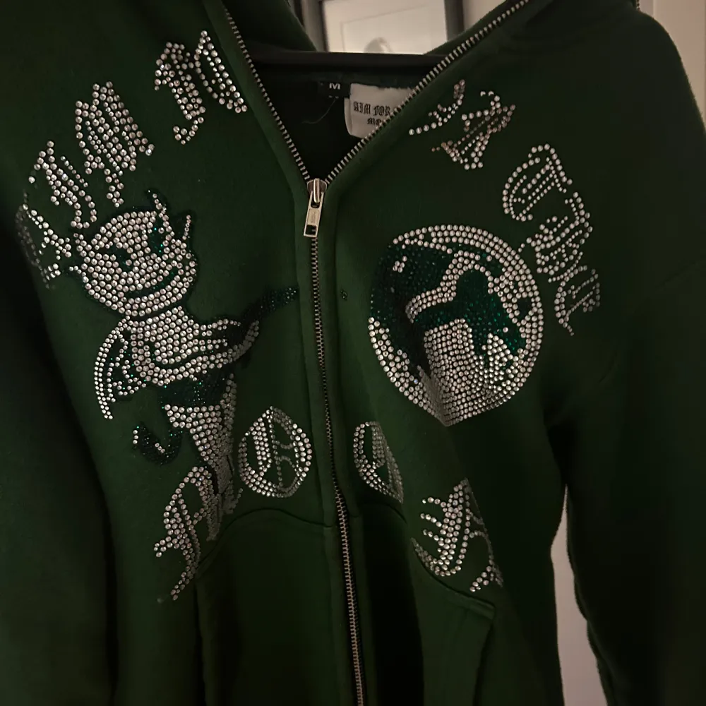 Säljer denna mörkgröna hoodie från ”Aim for the moon”.  Den är sparsamt andvänd i cirka 1 år. Saknas dock typ 3 pärlor på olika ställen, men inget som man märker av när man bär den.   storlek M    Hör av er om fler bilder osv! . Hoodies.