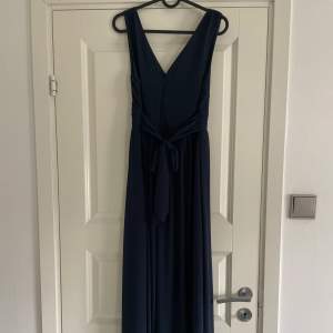 En lång mörkblå klänning från Vila i storlek 34. Går ända ner till fötterna.  Har ett knyte i midjan och är v-ringad både fram och i ryggen. Köptes för 800 och har används endast en gång. Säljer då den inte kommer till användning, men väldigt fin💞