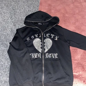 Kristall/diamant hjärt tröja hel svart  - Ett hjärt logo som gjord av kristall bitar som lyser upp när ett liknande ljus lyser på den.  STORLEK: M Köpt för cirka: 700kr  Skönt material och använd ett par gånger men inte nu längre för den har blivit för liten.