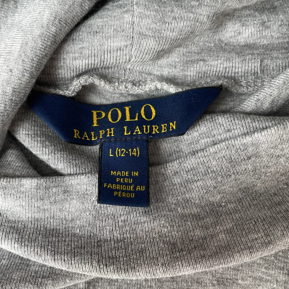 En fin grå polotröja från Ralph Lauren med ett Ralph Lauren märke på vänstra bröstet. Tyvärr har den en liten fläck längst ner i vänstra hörnet som förmodligen går att tvätta bort!. Tröjor & Koftor.