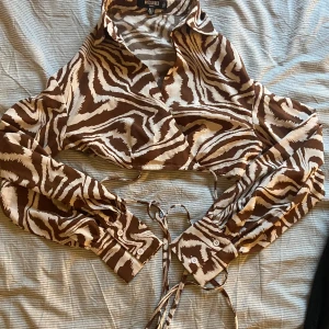 Blus till sommaren - Superfin blus som är sparsamt använd. Inga defekter och superbra kvalité. Knyts runt midjan eller lite som man vill. Otroligt cool färg. Storlek 38 men passar även större eller mindre beroende på hur man vill att den ska sitta. Fraktas mot kostnad 