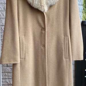 Fin ullkappa - Säljer en jättefin beige kappa, kvartslång.  Det är 80 % ull, den har fuskpäls på krage, knäpps med tre knappar. Mycket sparsamt använd och väl omhändertagen, så väldigt fint skick. Cappuccini strl 36. 450 kr 