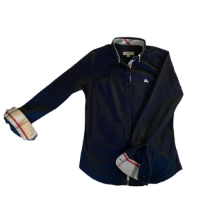 Burberry skjorta - Burberry skjorta i mycket bra skick. Färg: mörk blå Storlek: XS, står (s) på taggen men sitter som XS.  Vid frågor om fler bilder osv så är det bara att skriva.