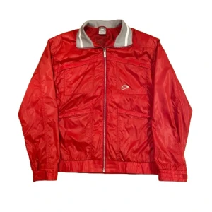 Nike vintage jacka ”wet look” - Vintage Nike jacka med sjukt coola detaljer. Perfekt för vårsäsongen. Jackan är sparsamt använd, enda defekten är en svart fläck på ena ärmen, märks knappt när man har den på. Skriv om du vill ha fler bilder eller mått! Stlk L men passar mer som M.