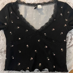 Kroppad T-shirt med blommor  - Säljer dennna fina kroppar T-shirten med blommor och detaljer, för liten storlek för mig, i bra skick.💗 storlek xxs