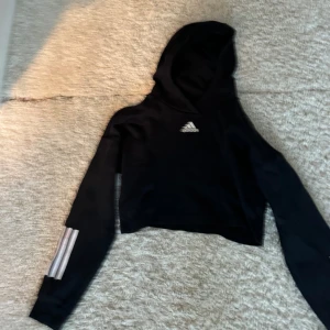 Adidas croppad svart Hoodie - En fin Adidas Croppad hoodie i nyskick, har inte använts många gånger. 
