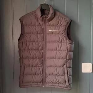 Brun dunväst från Peak Performance - En svart dunväst från Peak Performance i storlek S. Helt ny.