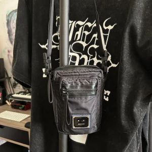 Acne Arvel Face Shoulder Bag - Tjusig och slick miniväska från Acne i gott skick. Den är flitigt använd men har inga fläckar eller tecken på slitage. Perfekt för sommaren!! 