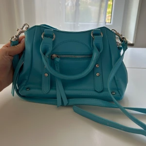 Ljusblå crossbody väska - Jättefin crossbody väska från Na-kd. Säljer den pga att den inte används. Den är knappt använd och i mycket bra skick.