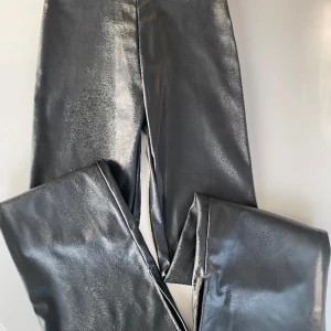 Svarta skinnleggings tjej strlk. 152 - Snygga svarta skinnleggings (ej äkta skinn). Bootcut modell, dvs utsvängda nedtill. Snygg slits som detalj vid benslut. Storlek 152 från H&M. Väldigt fint skick. Rök- & djurfritt hem. 