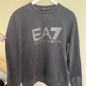 EA7 Sweatshirt - Riktigt snygg Emporio Armani sweatshirt som är mörkblå. 🔵  Inga defekter. Bara autentikationslappen är lite sliten av tvätt. Säljer pga börjar bli lite för liten  Köpare står för frakt 📦 