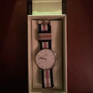 Säljer min Daniel Wellington klocka. Den är i silver och bandet är vitt, blått och rosa. Skriv till mig för mer bilder eller info! 🫶🏼