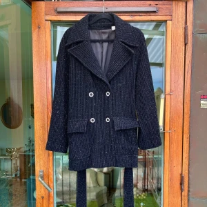 Svart glitter kavaj från Gibi Roma  - Svart vintage kavaj från Gibi Roma.   Material i rå ull.  Storlek 38  Har små glitter detaljer över hela kavajen och kristaller i knappar.  Dubbelknäppning framtill och en bälte i midjan.  Två fickor framtill.   Myceket gott skick🌈