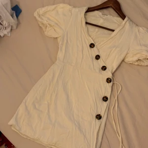Vit klänning str 34 - En vit omlott klänning med  knappar  jätte söt tyvärr för liten på mig. Str xs dvd 34