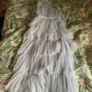 Balklänning - Ljusblå balklänning med volanger. Använd en gång men lite tecken på användning men inget som förstör eller syns. Köpt från ASOS. Storlek 38.