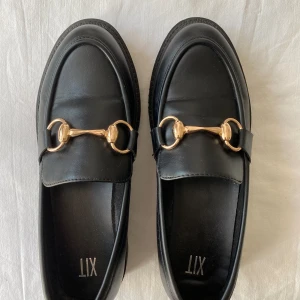Svarta loafers, st. 38 - Supersnygga svarta loafers med gulddetalj. Endast använda ett fåtal gånger så är i mycket gott skick!