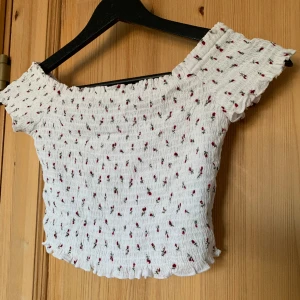 Blommig crop top  - Småblommig crop top med off-shoulder-ärmar. Stretchigt material. Märkt M men passar nog bättre på XS-S.  Längd 26cm