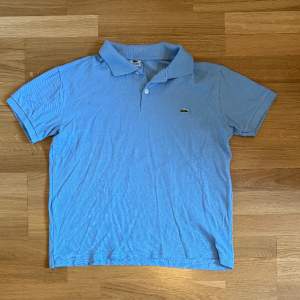 Blå Lacoste polo i storlek M säljer pga den inte kommer till använding och haf en knappt synlig fläck vid vänstra axeln. Annars inga problem och inte använd alls, fick den som present.