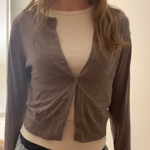 Grå/brun stickad kofta - Säljer denna fina kofta från hm som inte kommer till användning. I fint skick men är pyttelite nopprig men det syns knappt, skriv om du vill ha bild på de!