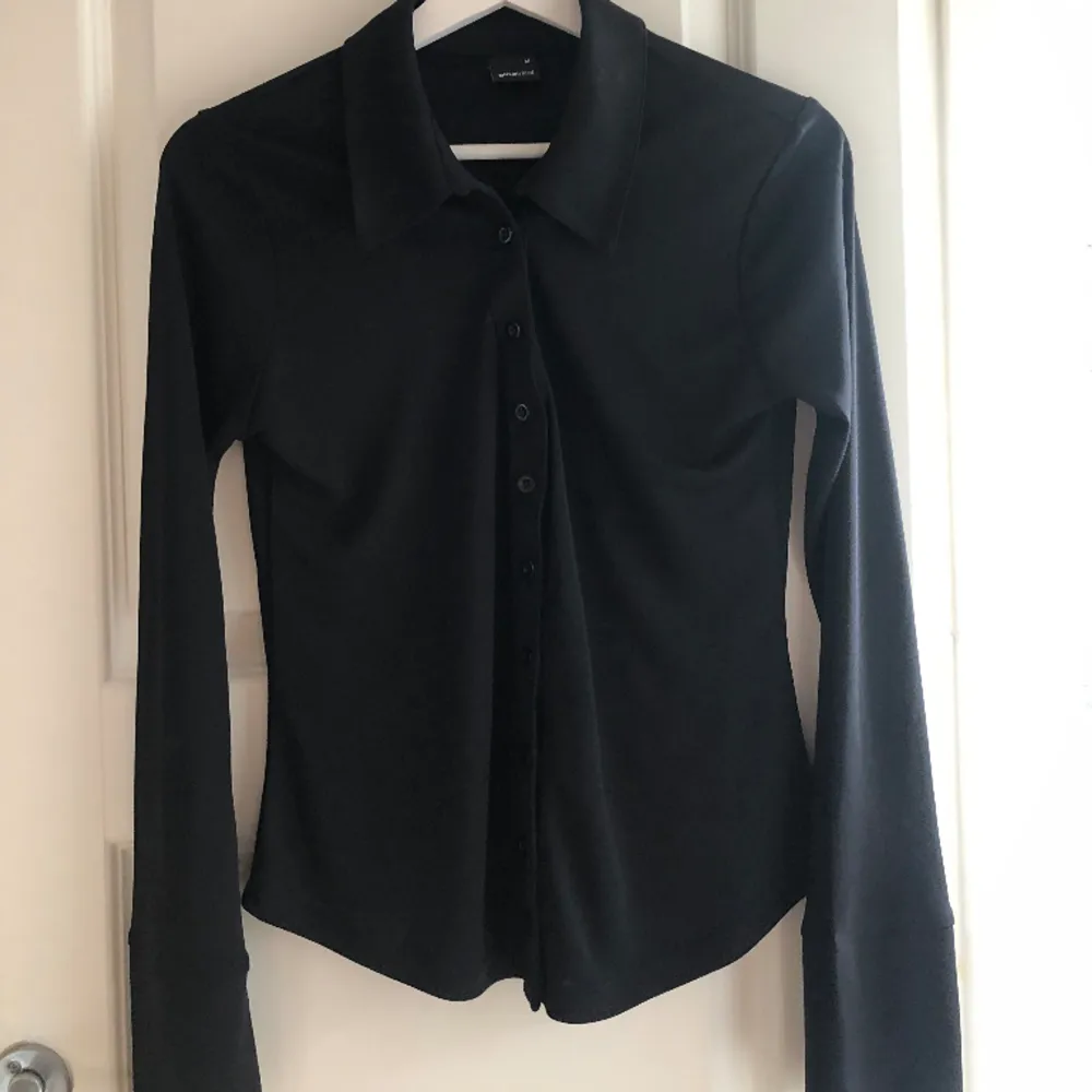 En svart blus som är lite skjortliknande i modellen men har ett väldigt mjukt och skönt material, den är knappt använd!😊🌟. Tröjor & Koftor.