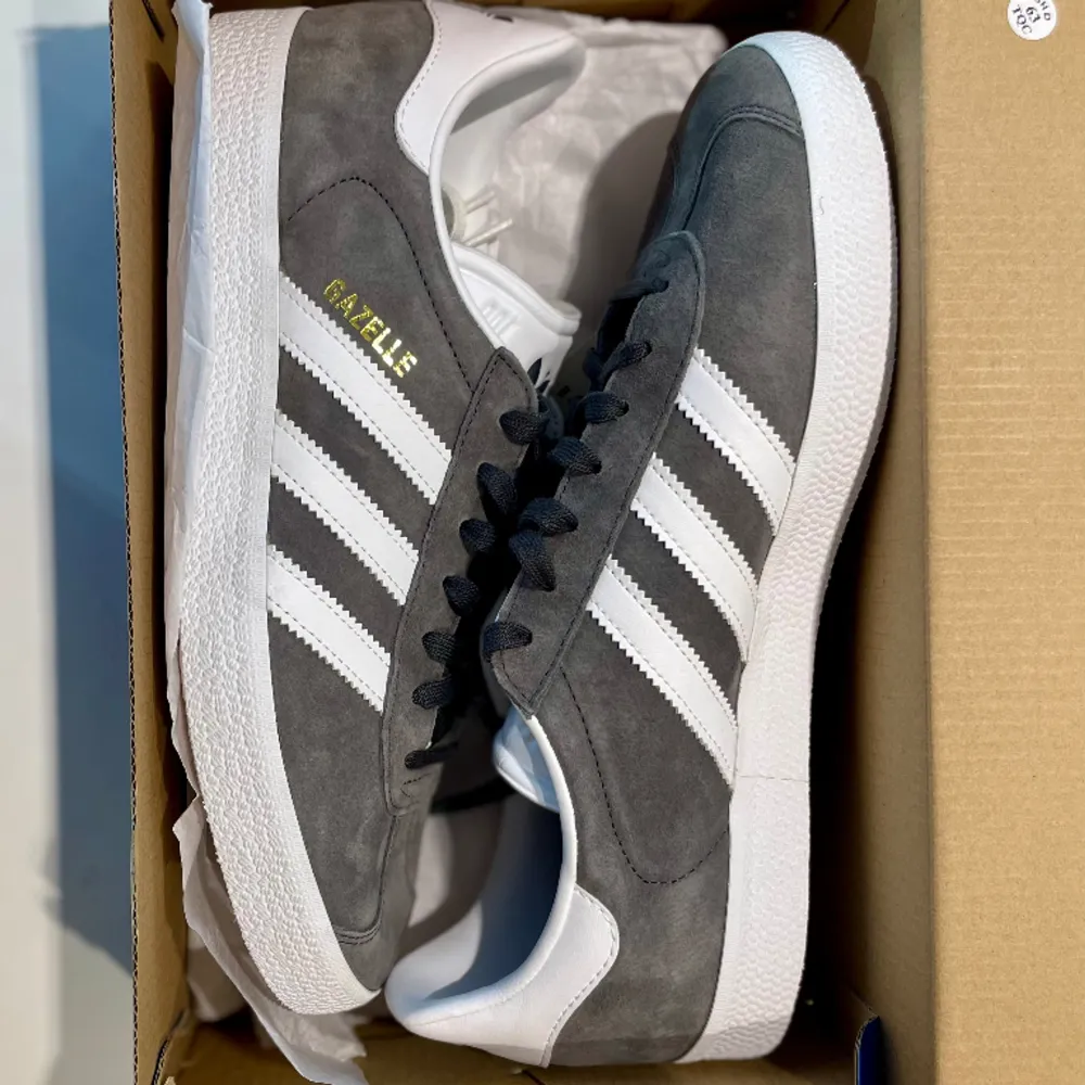 Ett par en-gångsanvända Adidas Gazelle skor i ljusgrå färg. Kvitto och låda finns kvar. Perfekta för våren!. Skor.