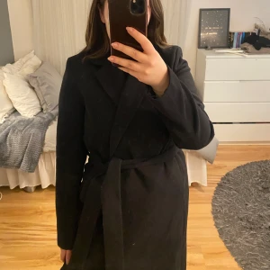 Kappa  - Jättefin kappa från H&M med ett band att knyta för att markera midjan. Kappan är i storlek 38 och den är normal i storleken. 