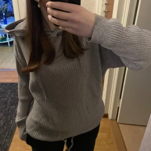 Stickad tröja - Grå finstickad tröja med luva. Även justerbar nertill. Endast använd en gång därav nyskick!