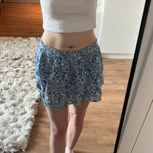 Blommig skjol - Super söt vit sommar kjol med blå blommor. Kjolen är i storlek XS och är köpt från bikbok. Använd ett fåtal gånger så kjolen är i mycket bra skick.