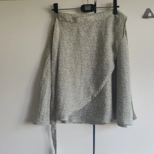 Omlottkjol - Ljusgrön blommig omlottkjol, storlek 36 men passar nog 34 och 38 med eftersom den knyts. Dubbelt tyg