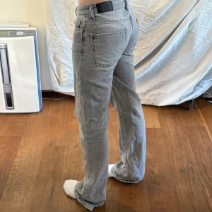 Grå jeansbyxor - Ett par grå jeansbyxor i storlek xxs. Byxorna har en rak passform och är lågmidjade . De har klassiska fem fickor och stängs med dragkedja och knapp.