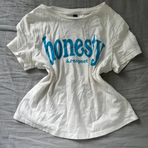 Vit T-shirt med tryck - Vit T-shirt med blå text som knappt är använd. 