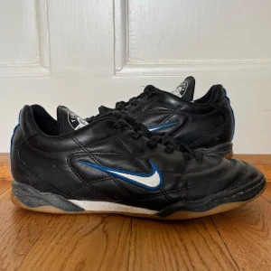 Nike Tiempo 750 - Svarta skor med blå och vita detaljer från Nike. Fint skick ( de är vintage men jag har aldrig kunnat använda dem ). Innermått ca 25cm. Hör av dig vid frågor👼