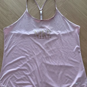 Ljusrosa linnetopp från Nike - Säljer en ljusrosa linnetopp från Nike i storlek XL. Perfekt för träning eller en varm sommardag!