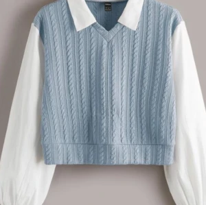 Ljusblå stickad väst - Säljer en superfin ljusblå stickad väst med v-ringning. Västen är croppad och har ett snyggt kabelstickat mönster. Perfekt att ha över en skjorta eller blus för en stilren look. Passar både till vardags och fest!