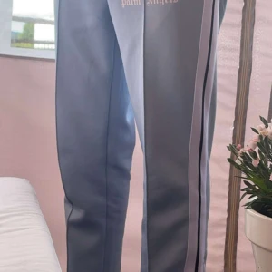 Grå mjukisbyxor från Palm Angels - Säljer ett par grå mjukisbyxor från Palm Angels. De har en snygg och bekväm passform med svarta ränder längs sidorna. Perfekta för en avslappnad stil eller träning. Byxorna är i bra skick och redo för en ny ägare!