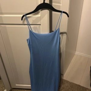 Ljusblå klänning från BikBok - En elegant ljusblå klänning från BikBok. Klänningen är ärmlös med smala axelband och har en enkel, stilren design.