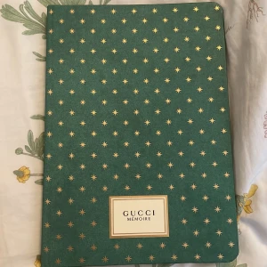 Grön anteckningsbok från Gucci - Säljer en snygg grön anteckningsbok från Gucci med ett stjärnmönster i guld. Boken har linjerade sidor och är perfekt för att skriva ner dina tankar och idéer. Den är i nyskick och har en lyxig känsla. Perfekt som present eller för egen användning! Det är en limiter edition så den är värd ganska mycket, jag fick den i present så är inte säker på priset, men jag har hittat andra säljare som säljer för ungefär 900 kr. Boken är nog i en kollektion med Gucci memoire d’une Odeur parfymen. den är helt oanvänd och har inga skador.